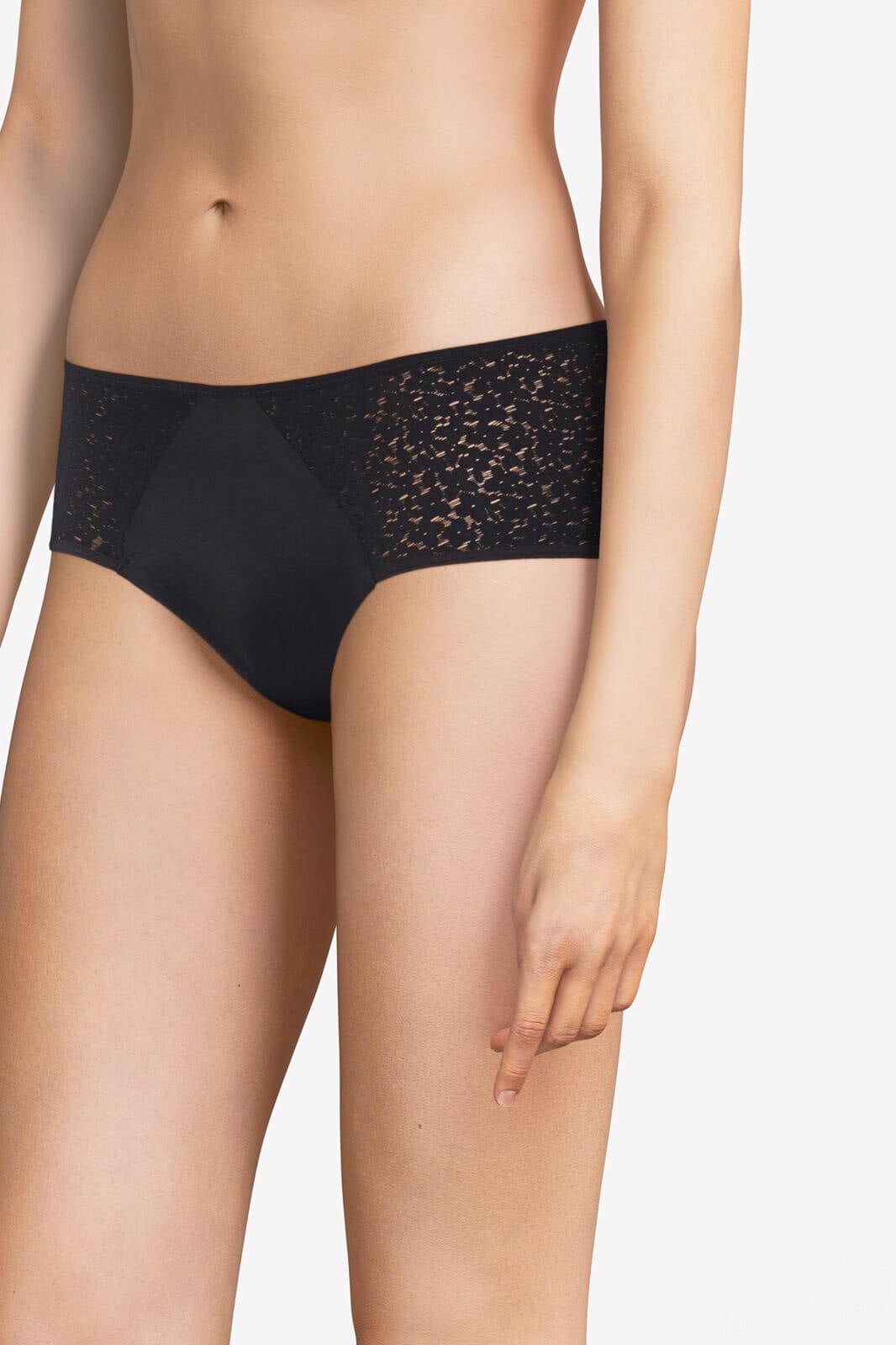 En kvinde viser Chantelle EasyFeel Norah Black Sort hipster-trusser frem, fra midten af overkroppen til låret, på en ensfarvet baggrund.