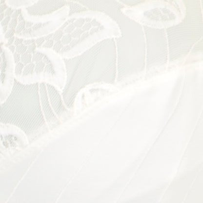 Nærbillede af blonderne på PrimaDonna Deauville Natur-bh’en: blomstermønstre, glat, off-white stof, detaljeret struktur og syninger.